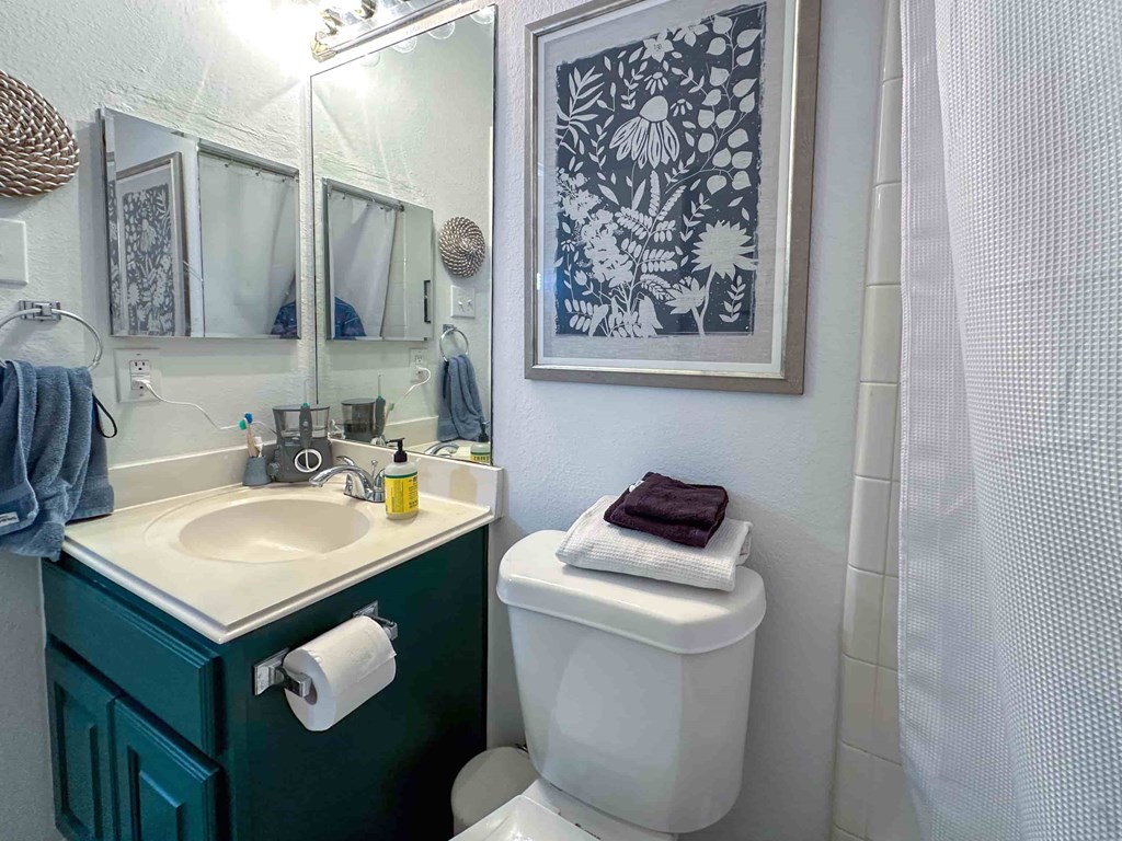 A bathroom with a green cabinet and a white toilet.