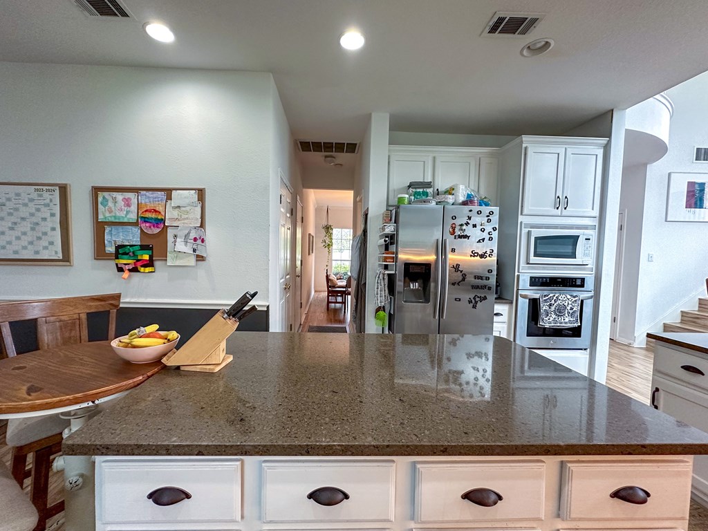 A kitchen with a table and a refrigerator with a magnet on it.