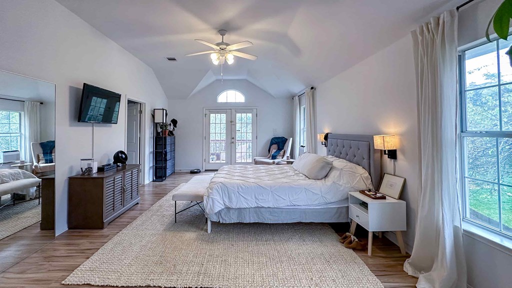 A bedroom with a large bed and a ceiling fan.