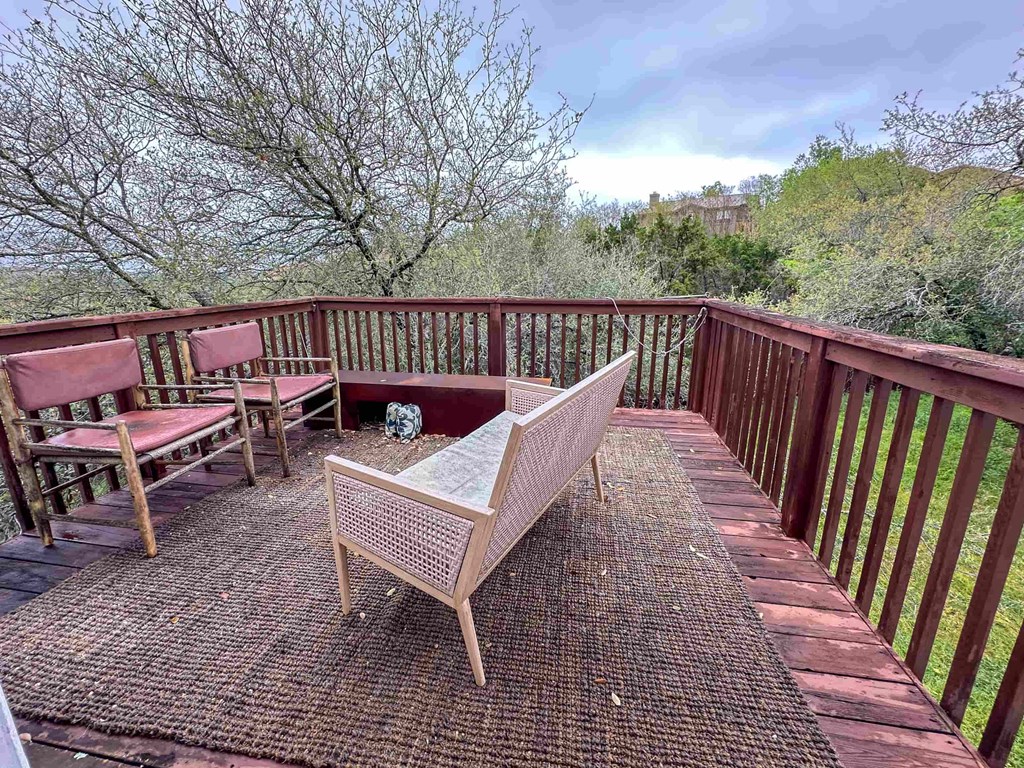 A wooden chair and table are on a deck with a railing.