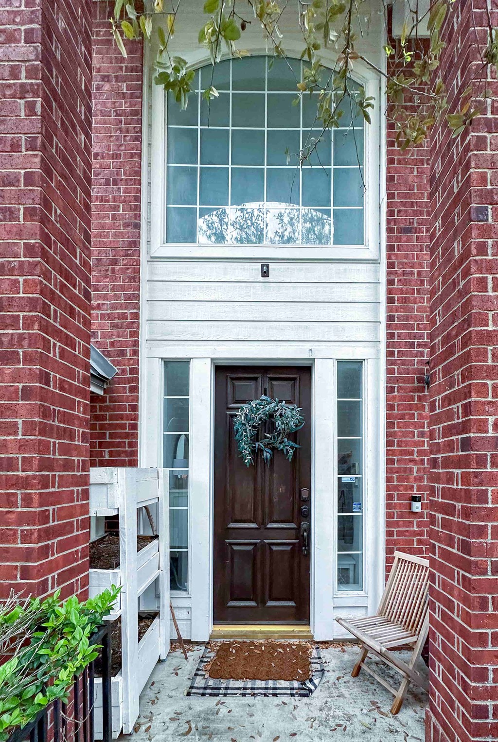 A red brick house with a wooden door and a wreath on it.