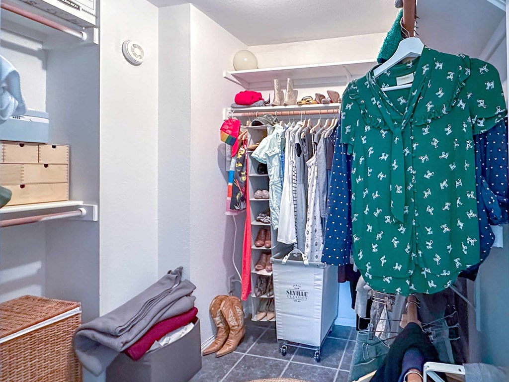 A green shirt with white flowers is hanging on a rack in a room.