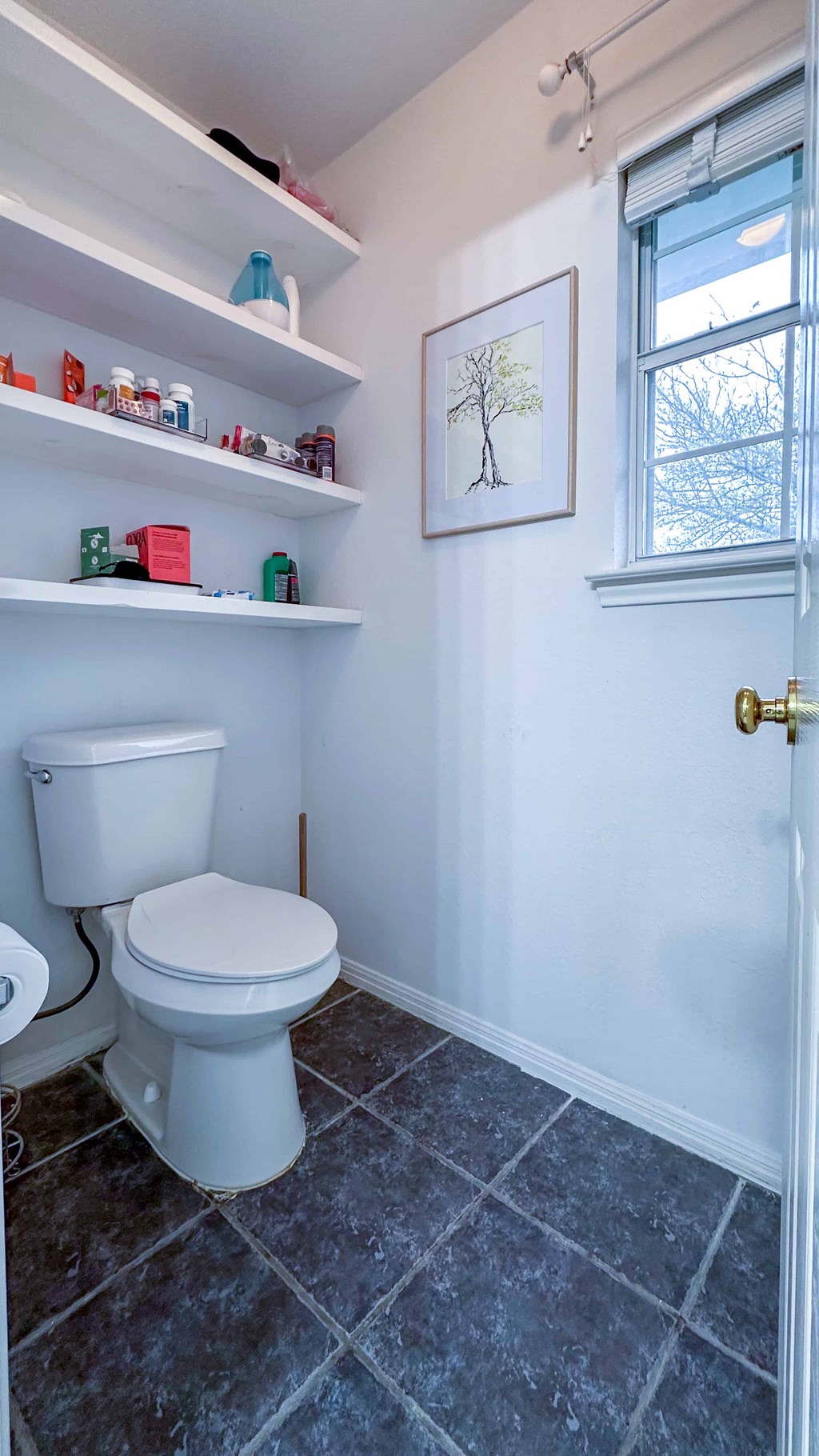 A white toilet in a bathroom with a white door and a window.