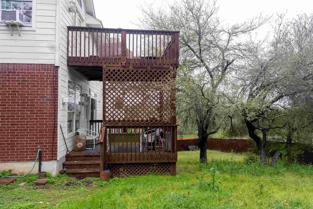 A wooden deck with a lattice top is in front of a house.