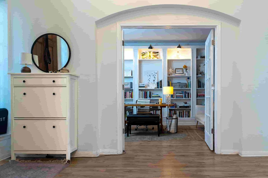 A room with a white dresser and a mirror on the wall.