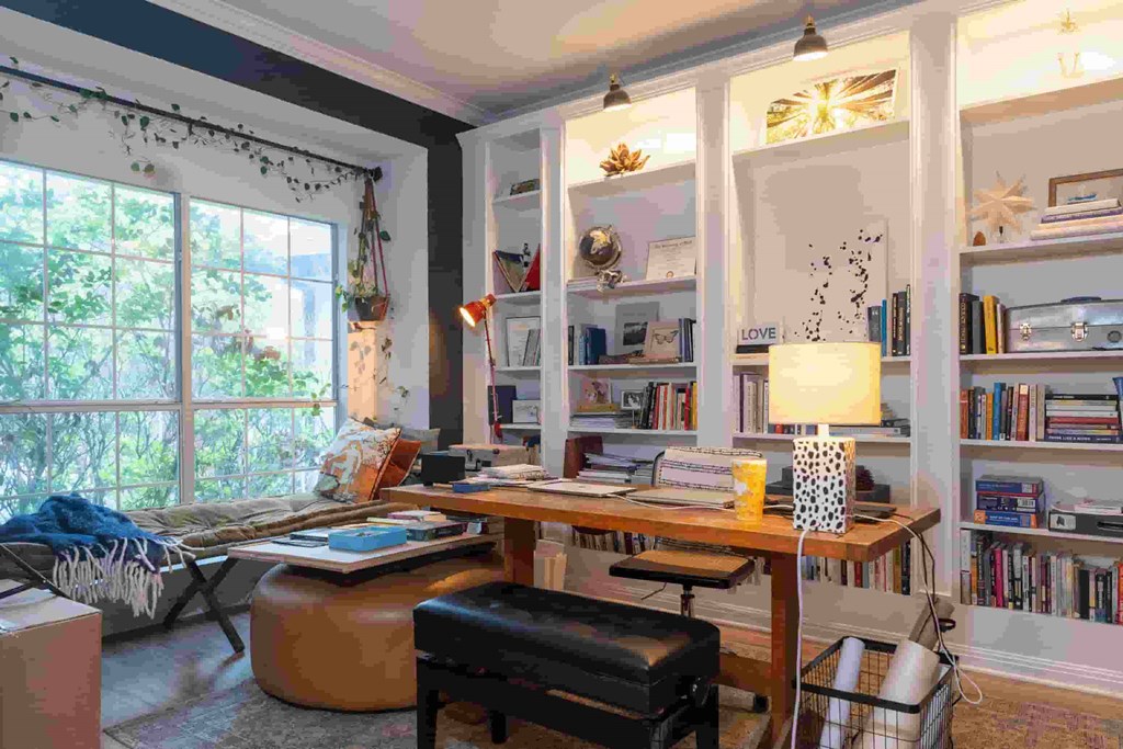 A room with a desk, chair, and bookshelf filled with books.