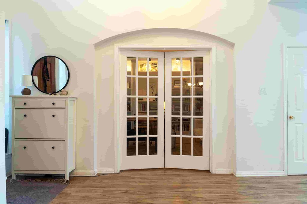 A white door with a glass panel is in a room with a wooden floor.
