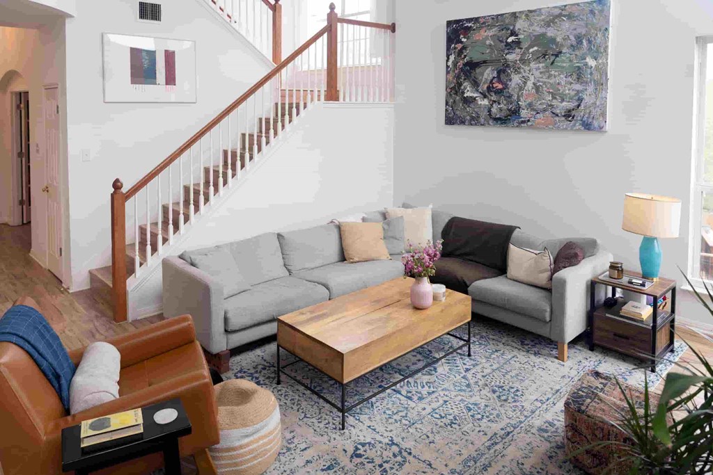 A living room with a grey couch, a wooden coffee table, and a painting on the wall.