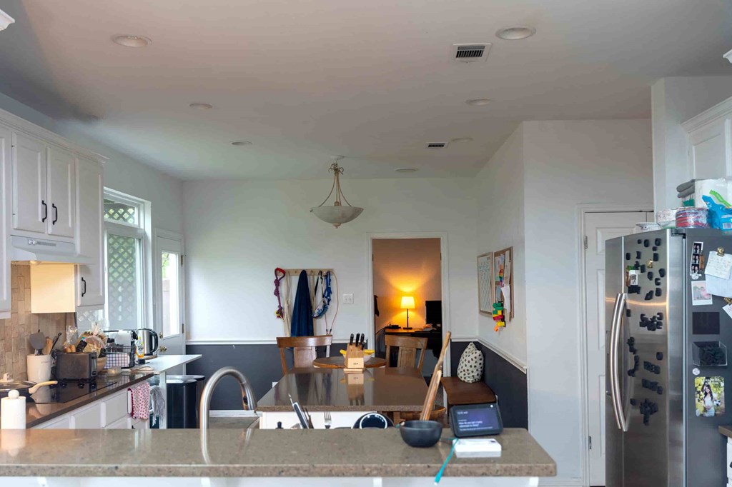 A kitchen with a refrigerator, sink, and a table with chairs.