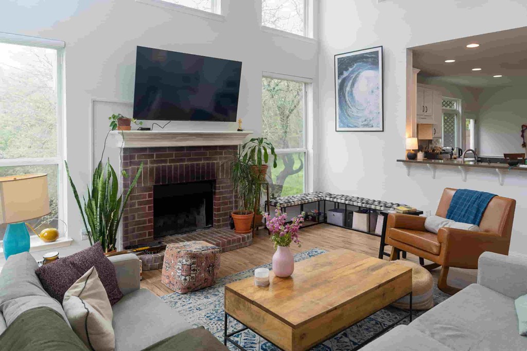 A living room with a fireplace and a flat screen TV mounted above it.