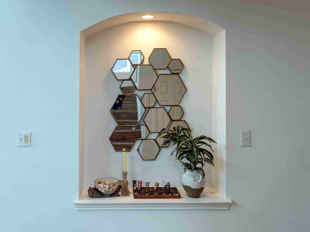 A wall-mounted shelf with a mirror and a potted plant.
