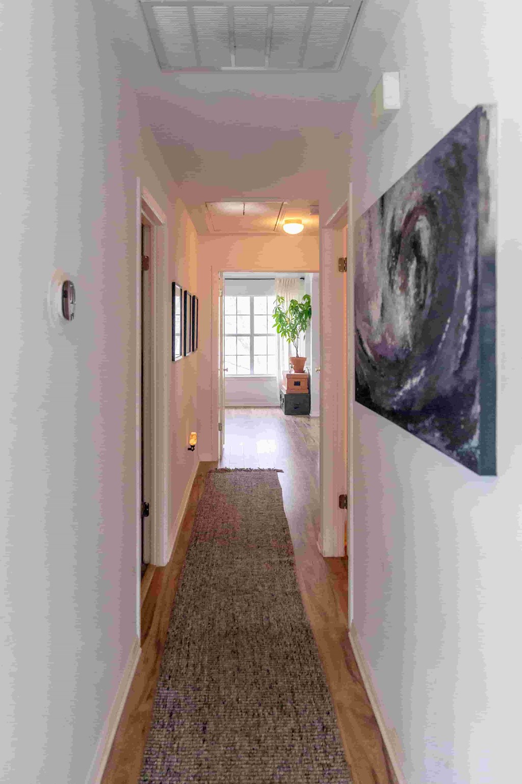 A hallway with a carpeted floor and a painting on the wall.