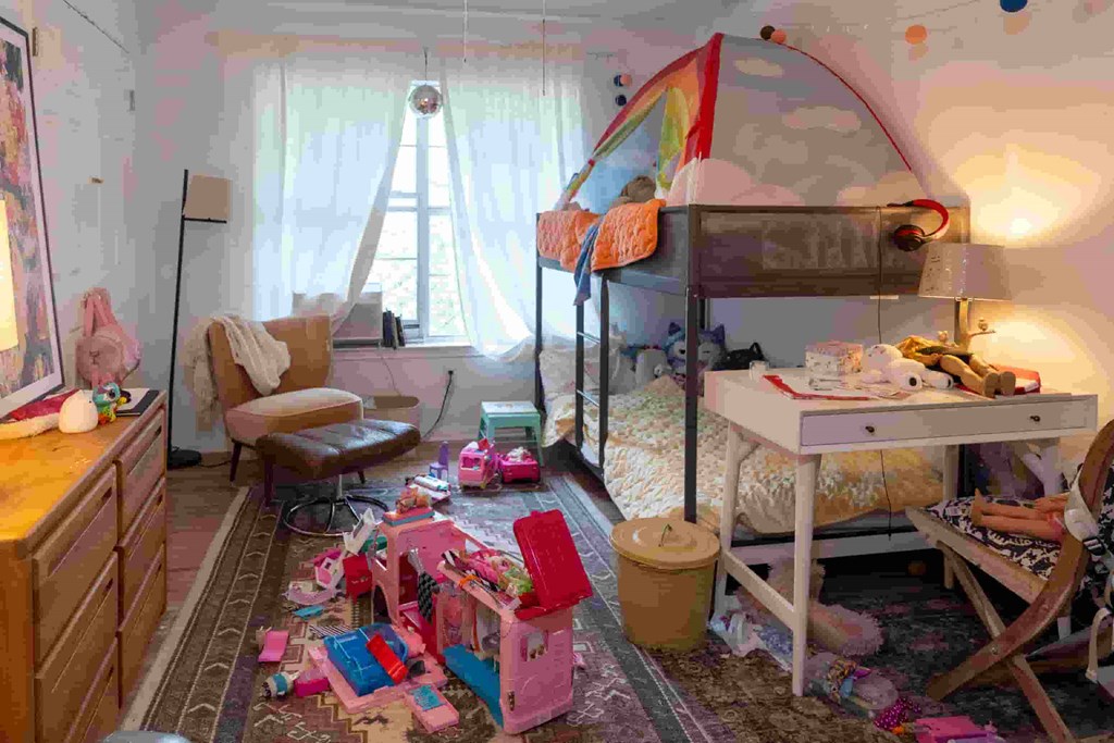 A messy room with a bunk bed, desk, and chair.