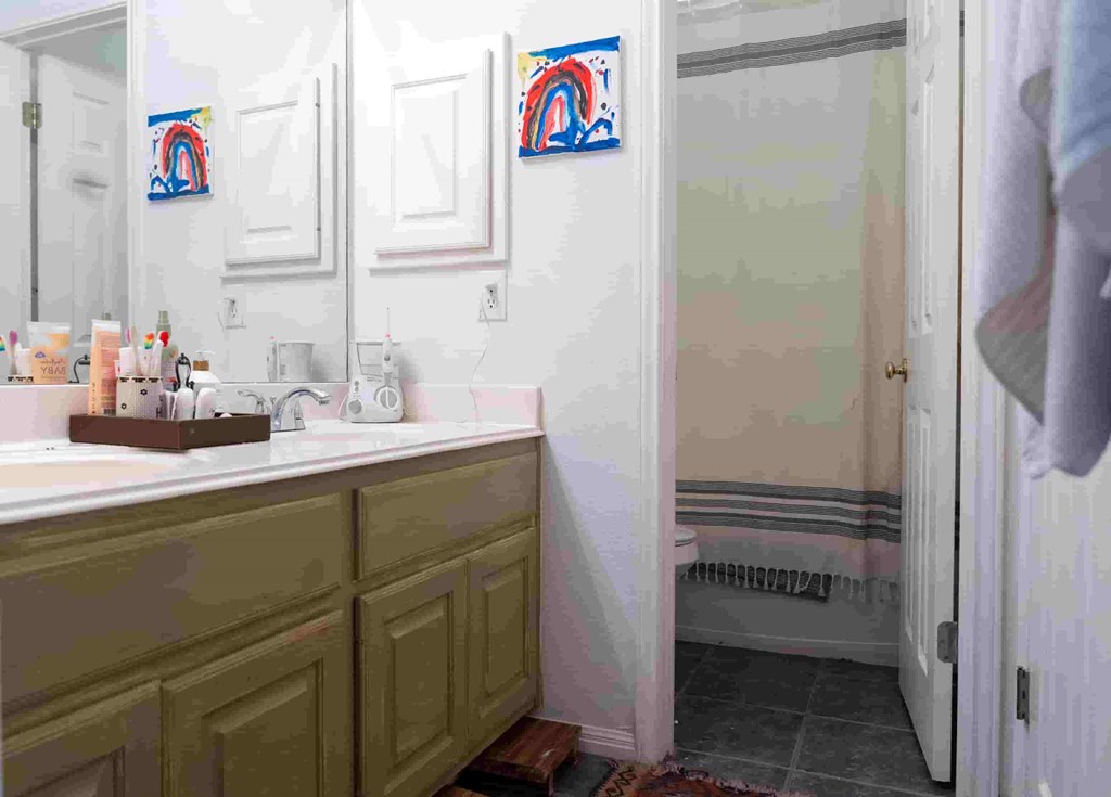 A bathroom with a green vanity and a white sink.