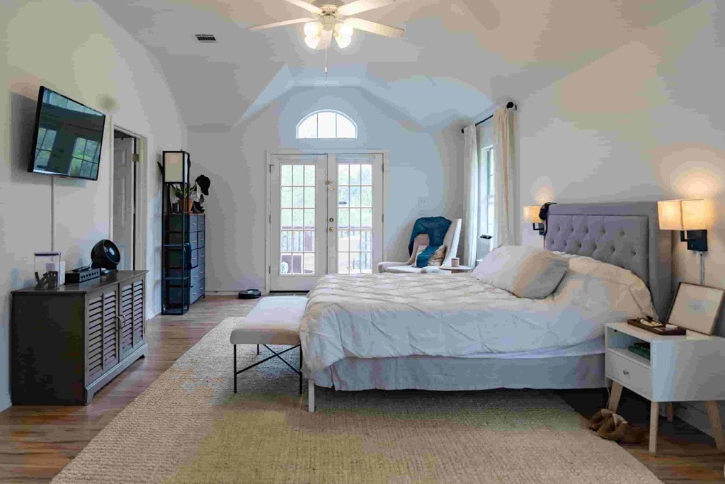 A bedroom with a large bed and a ceiling fan.