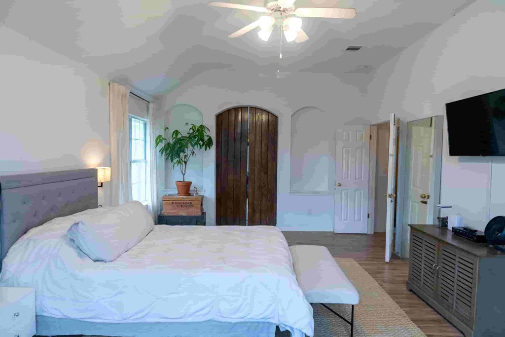 A bedroom with a large bed and a ceiling fan.