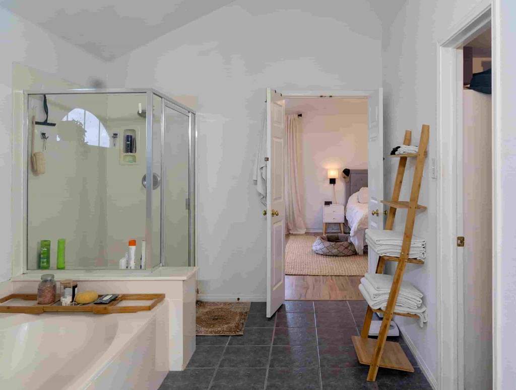 A bathroom with a glass shower door and a wooden ladder.