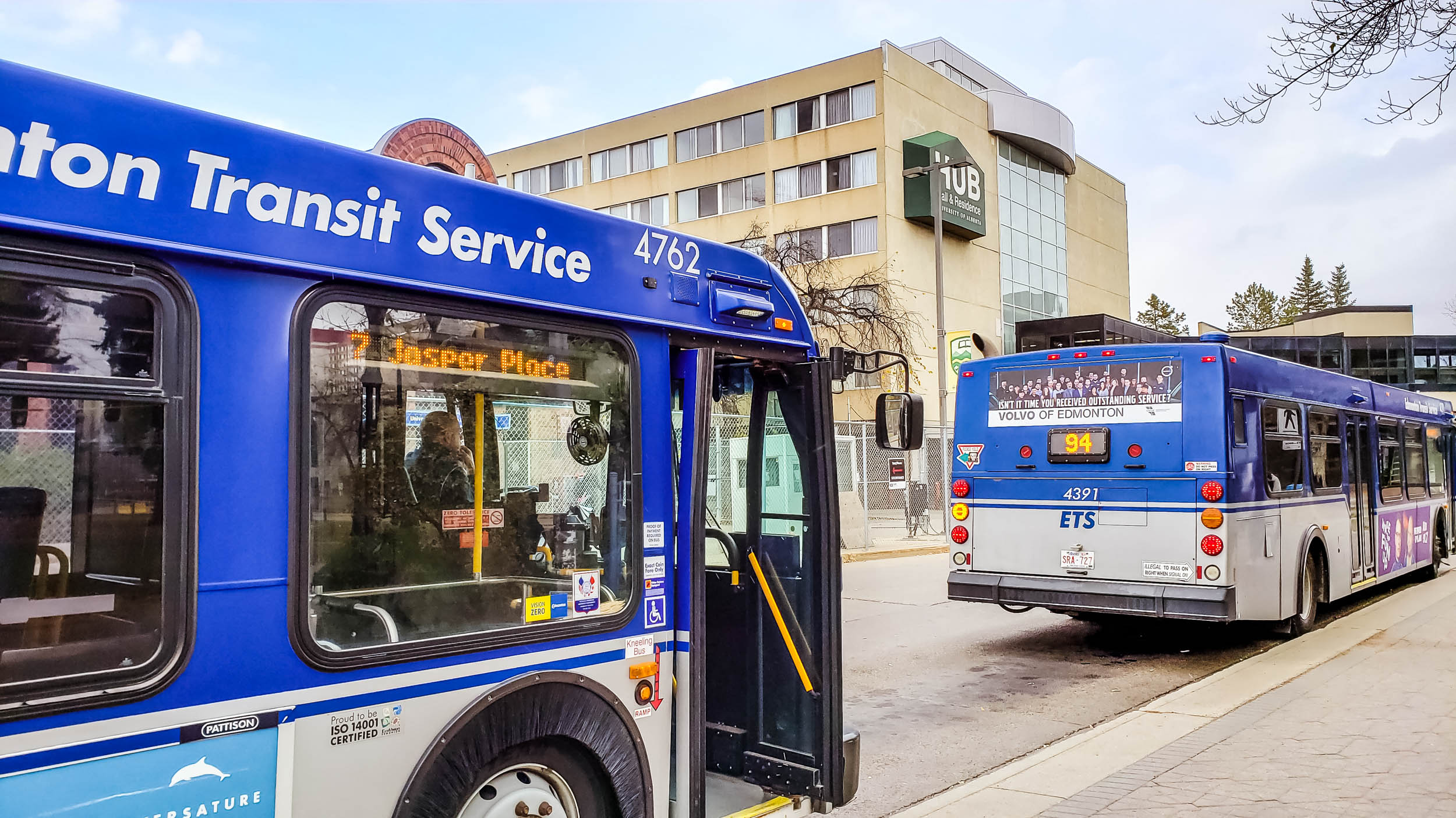 a blue bus and a white bus parked at a bus stop