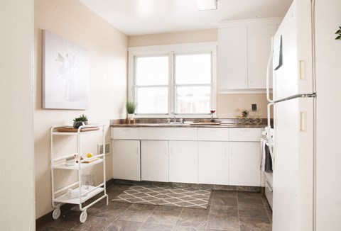 a small kitchen with white cabinets and a tile floor