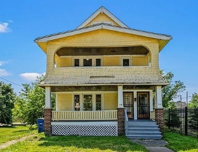 A yellow house with a black fence in front.
