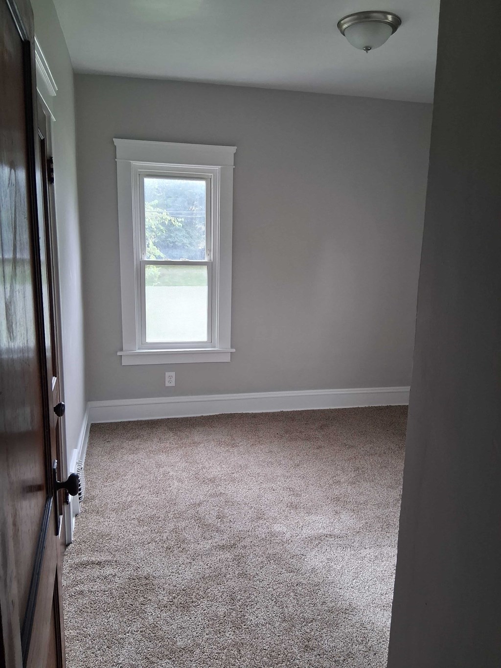 A room with a window and carpeted floor.