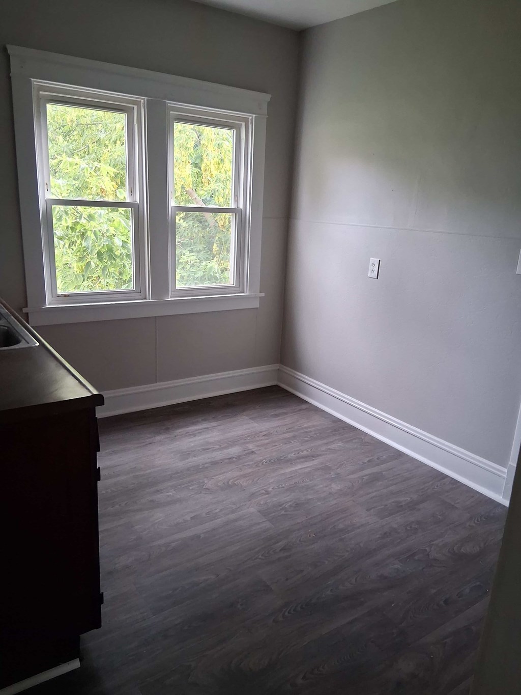 A room with a window and a wooden floor.