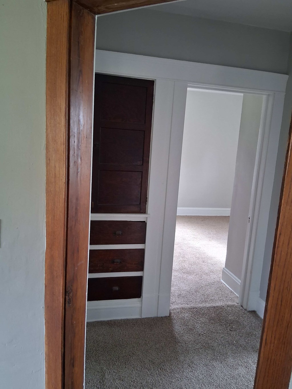 A white door is open to a room with a brown dresser.