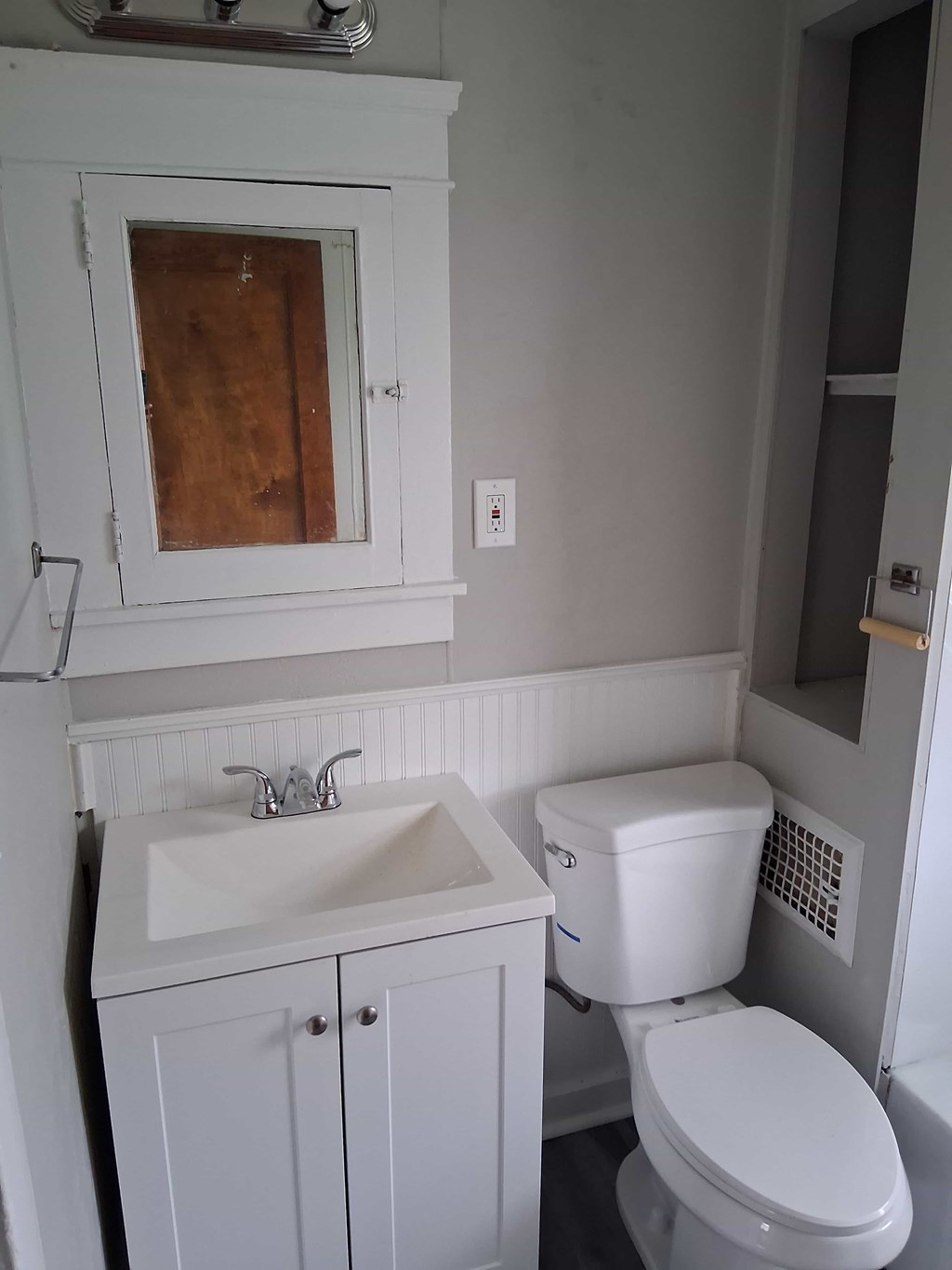 A white toilet sits next to a sink in a small bathroom.