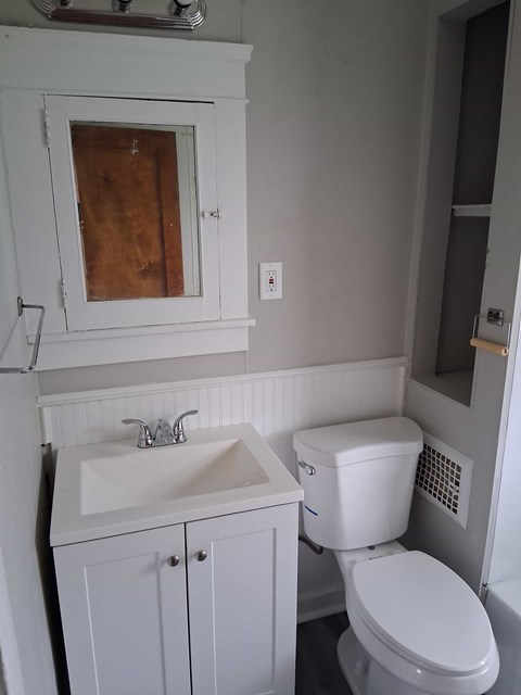 A white toilet sits next to a sink in a small bathroom.