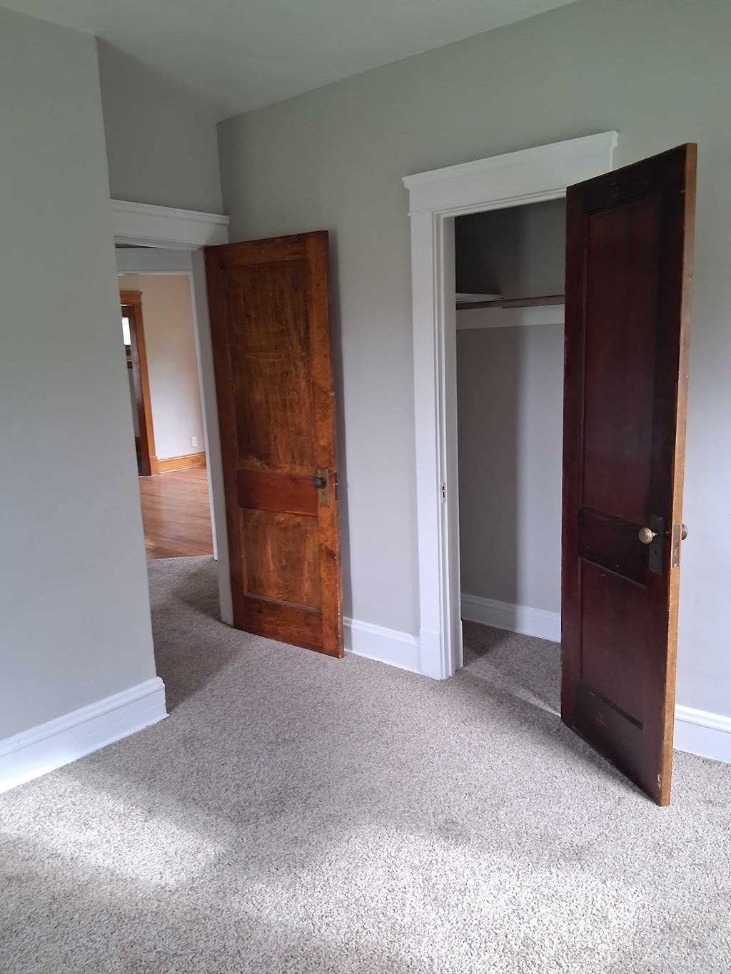 A room with a carpeted floor and a wooden door.