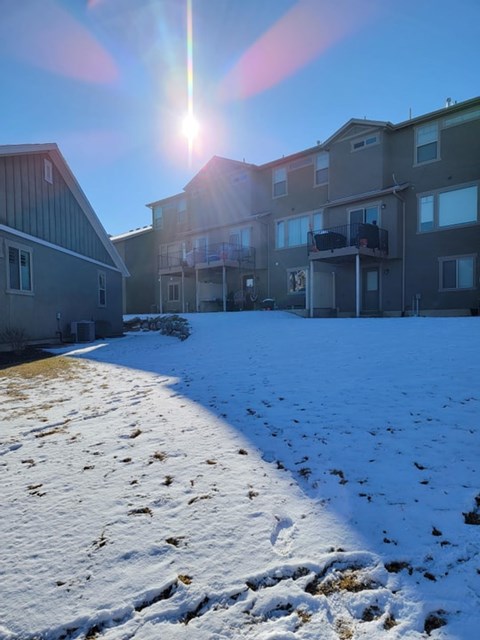 A sunny day in a snowy residential area with buildings on the left and apartment buildings on the right.