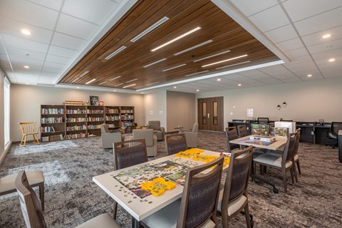 A room with a table, chairs, and a puzzle on the table.