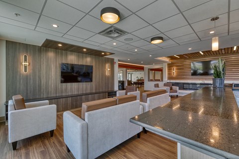 A modern living room with a long table and grey couches.