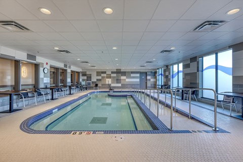 A large indoor swimming pool with a blue tiled edge and a white tiled floor.