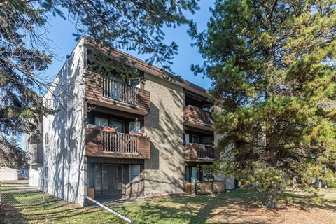 A building with a balcony and a tree in front of it.