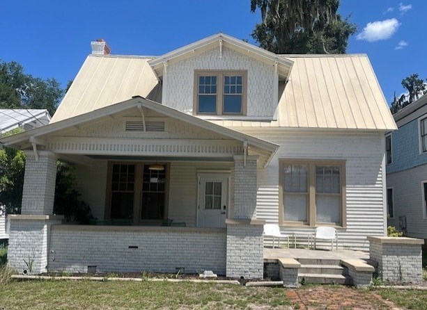 A white house with a porch and a covered entry way.