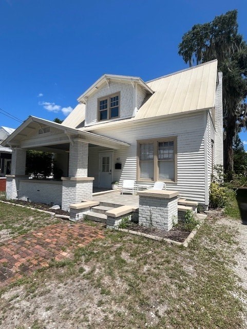 A white house with a porch and a covered entry way.