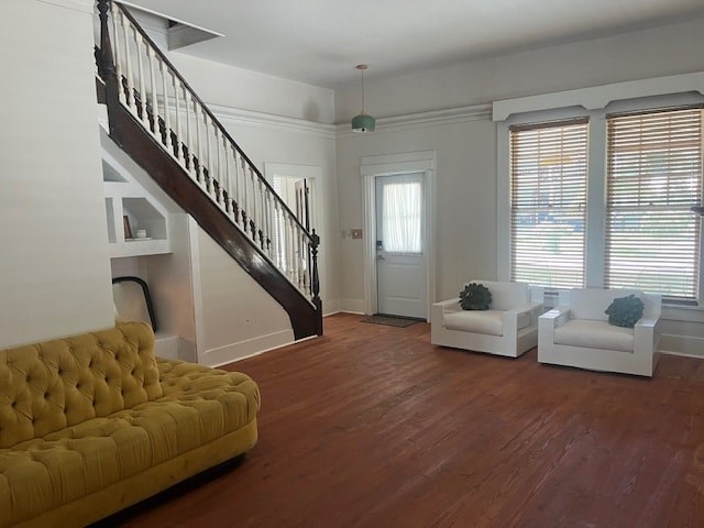 A yellow sofa sits in a room with a wooden floor and a staircase.