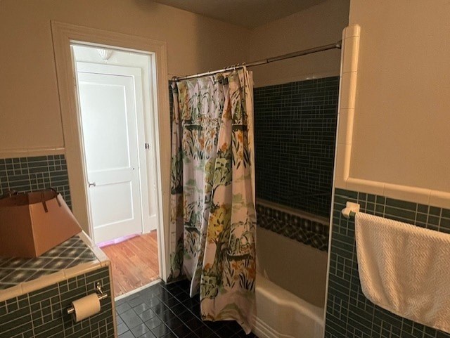 A bathroom with a shower curtain and a towel hanging on the wall.