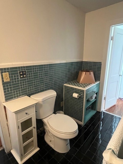 A white toilet with a cabinet and a roll of toilet paper in a bathroom.
