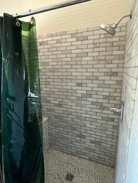 A shower with a green curtain and a grey tiled wall.