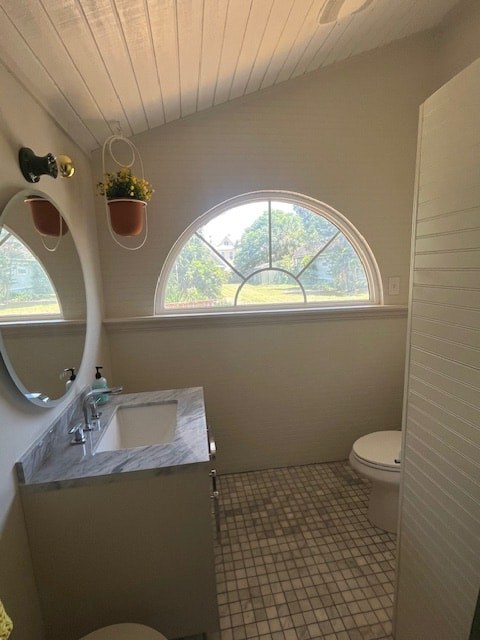 A bathroom with a toilet, sink, and a window.