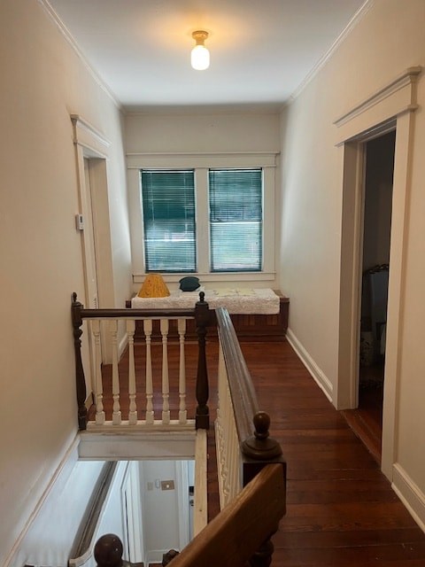 A long hallway with a wooden staircase and a window with blinds.