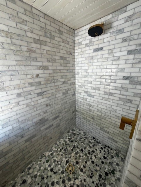 A bathroom with a tiled wall and a shower.