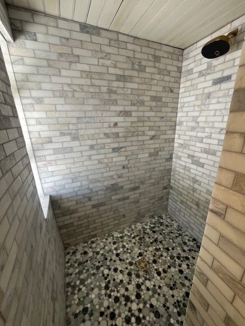 A bathroom with a tiled shower and a tiled floor.