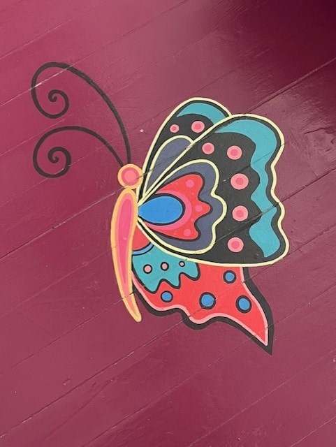 A colorful butterfly with blue and red wings is on a pink background.