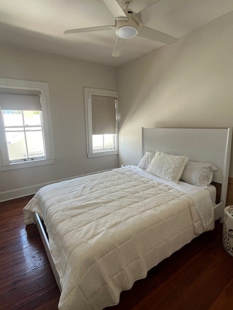 A bedroom with a bed, a ceiling fan, and a window.