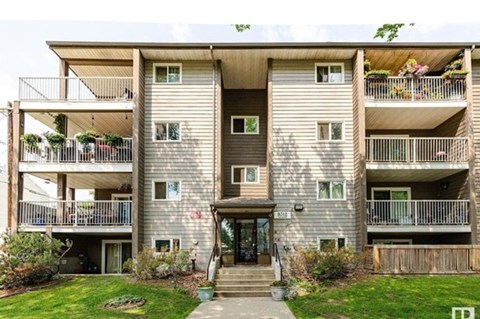A large apartment building with a green lawn in front.