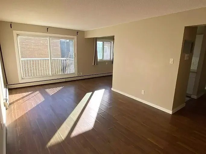 A room with wooden floors and two windows.