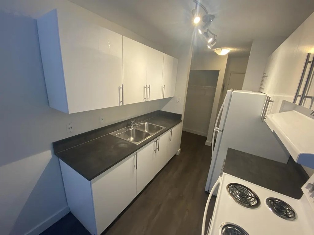 A kitchen with white cabinets and a black countertop.